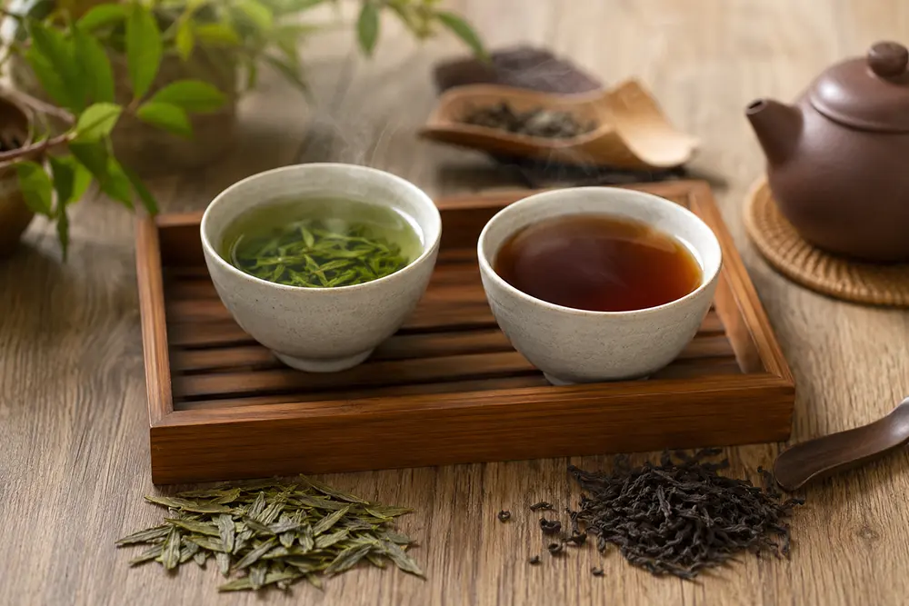 Photorealistic image of green tea and black tea cups on a tea tray with warm natural light.